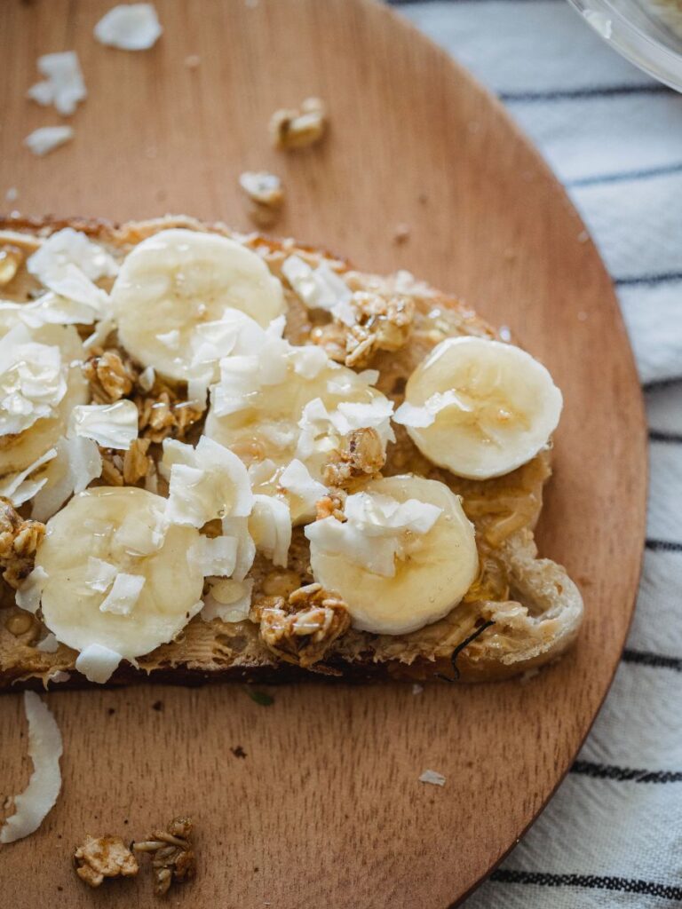 A slice of bread with peanut butter, sliced banana, and coconut flakes. This is my favorite small snack to eat before running.