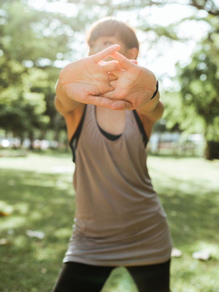 A girl is stretching her arms out in front of her body before exercising.