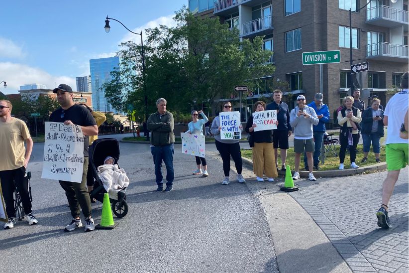 A group of spectators hold signs along a turn on the Nashville Rock 'n' Roll Marathon course. The signs read, "I don't do half marathons. I do a half marathon runner." "The force is with you." "Cheer if ur from Ohio."