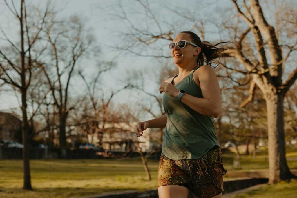 I'm running in a park wearing my goodr running sunglasses. The sunglasses are white with lightning bolt on them. goodrs are not expensive making them one of the best gifts for runners.