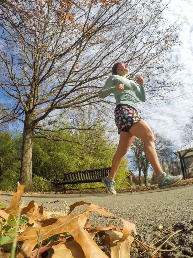 I'm running on a sunny, autumn day in Nashville, TN. I'm wearing my long-sleeved running shirt, running skirt with colorful hearts, and my running socks and shoes. I also have a running head warmed on and goodr running sunglasses. The tree behind me has almost no leaves left on it.