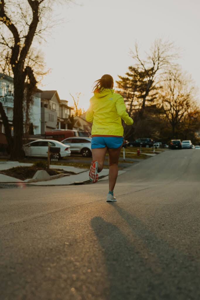 I am running away from the camera. The sun is setting in front of me behind a row of homes and tress on a neighborhood street.
