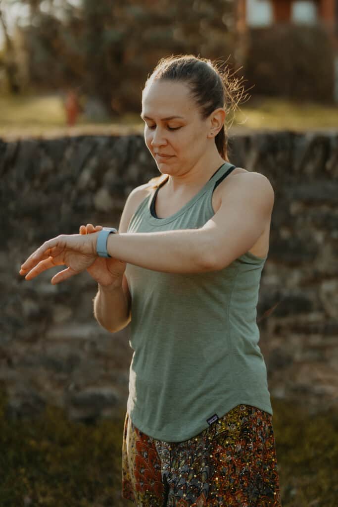 I'm standing in a park wearing my running clothes preparing to run. I'm looking at the Apple Watch on my wrist. My face doesn't appear to show any happiness, something that may occur as a symptom of running burnout.