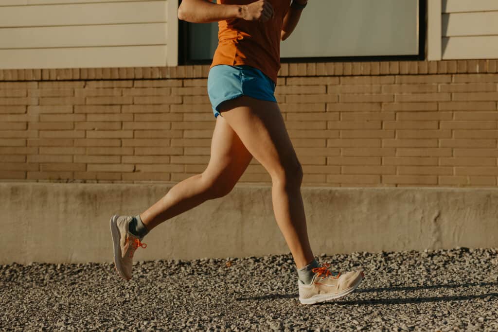 From my waist down my legs are running on a gravel path wearing my running clothes on a sunny day.