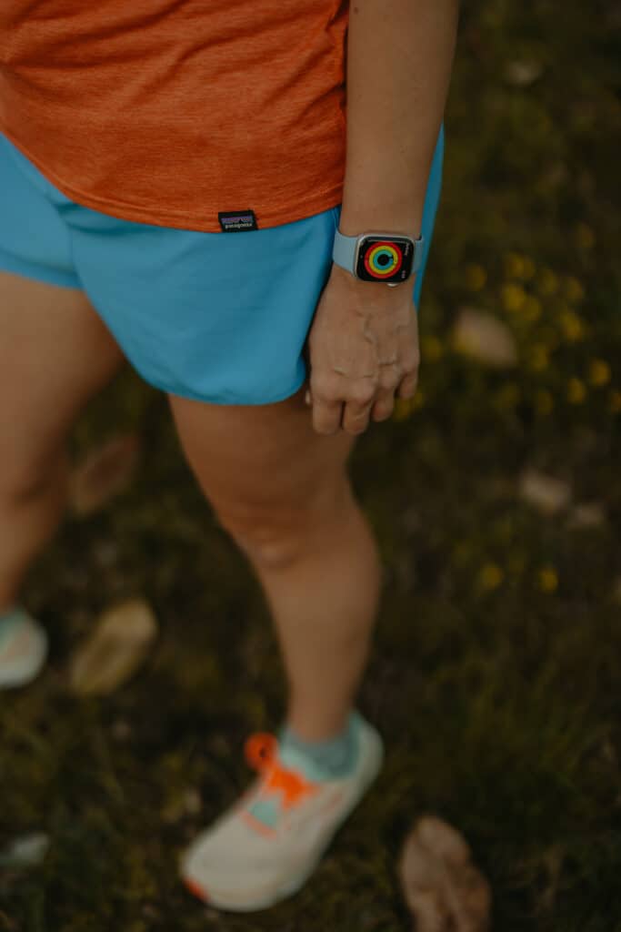 A view from my waist down, I am wearing my running clothes and my apple watch. My apple watch is displaying my activity rings for the day.